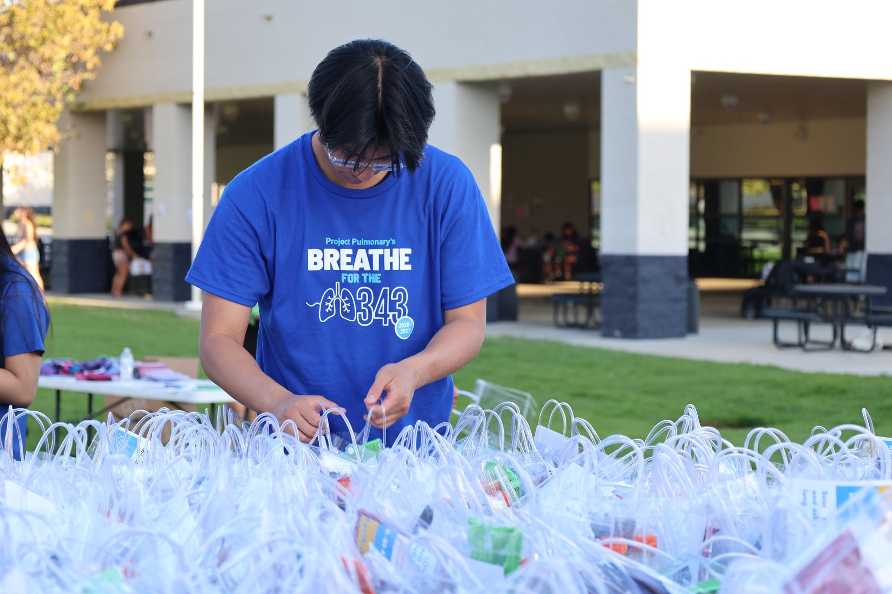 A volunteer packing kits behind rows of finished bags