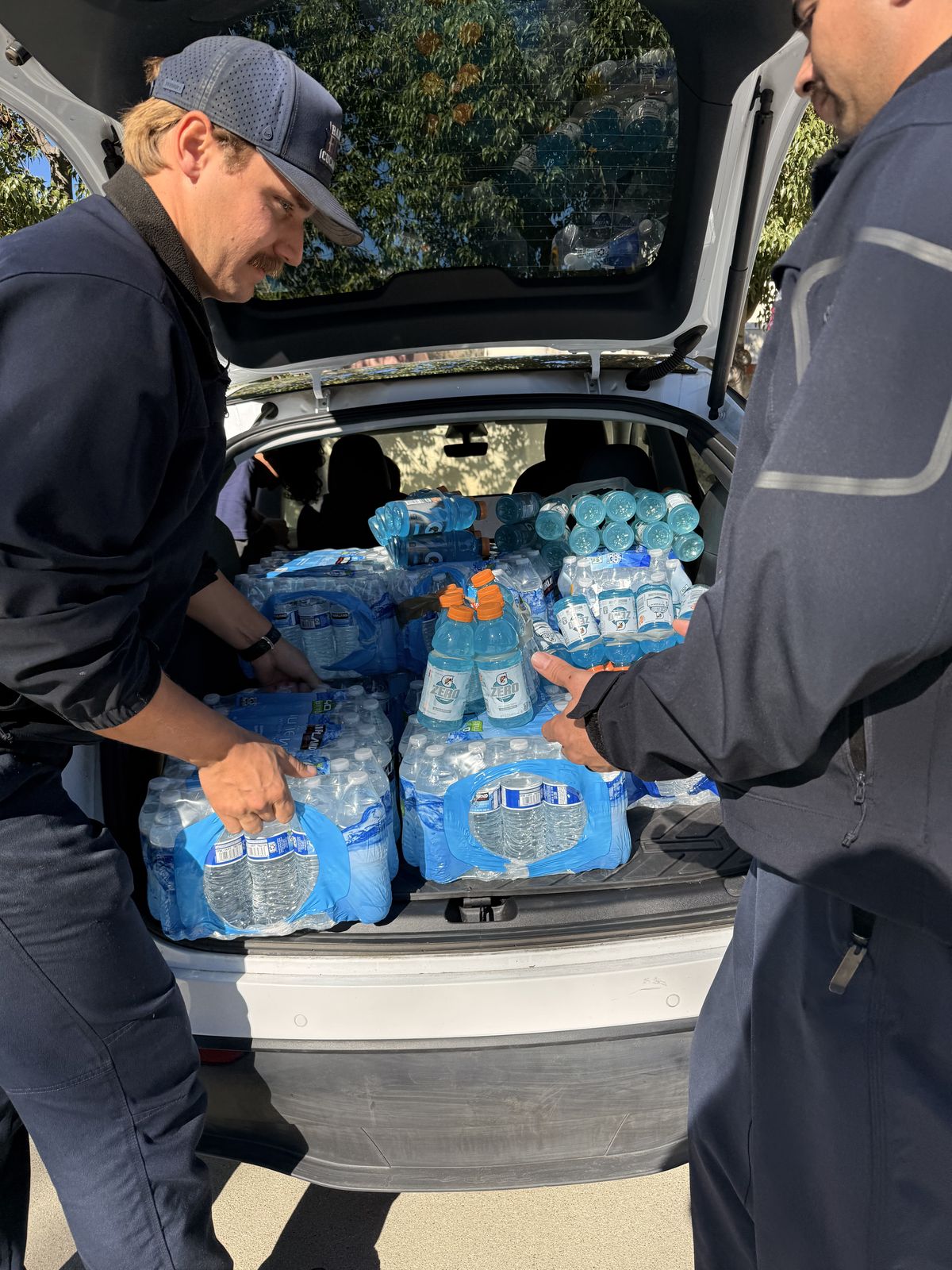 Firefighters unloading cases of donated water from a volunteer's car