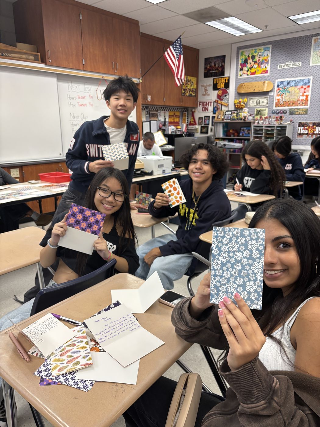 Students holding up handmade cards in class