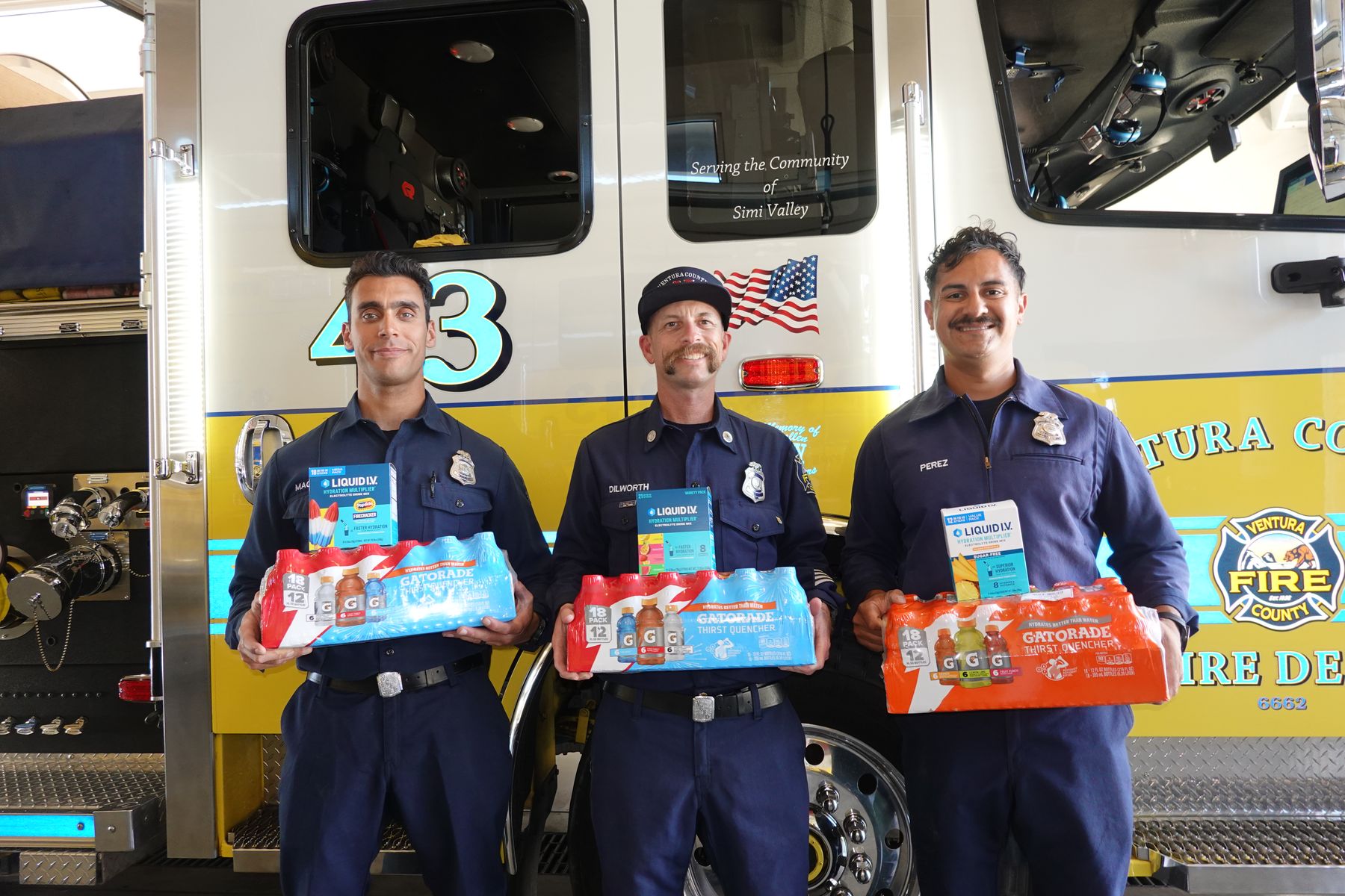 Three Ventura County firefighters holding donated hydration packs in front of Engine 43